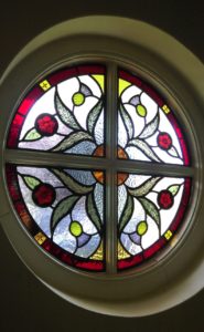 Round window featuring rose and thistle design for house in Chertsey, Surrey.
